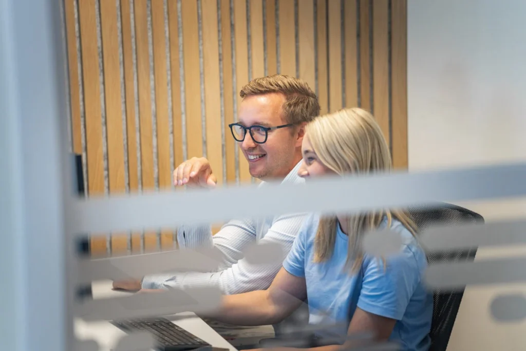 Två medarbetare på GoProfessional hjälps åt framför en dator