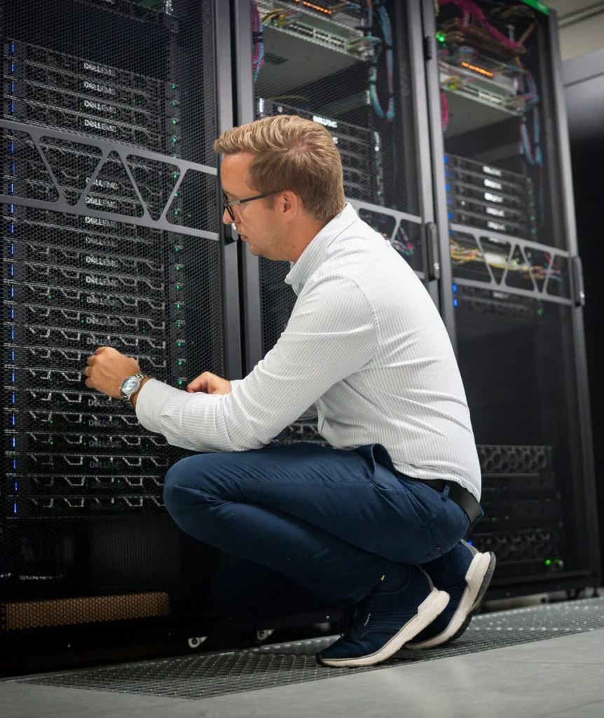 Tekniker sitter på huk och arbetar vid ett serverrack