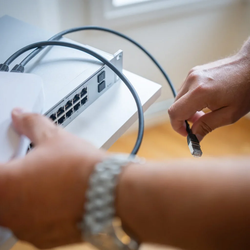 Händer kopplar nätverkskablar till en switch